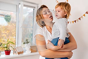 A whimsical child. A young mother hugs and comforting her crying baby. The concept of parenting