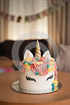 A whimsical unicorn-themed cake adorned with colorful frosting roses and a golden horn takes center stage on a birthday