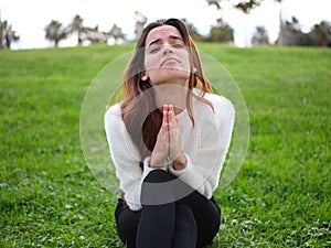 A whimsical woman holds her palms together and looks at camera with an imploring expression asking for a favor.