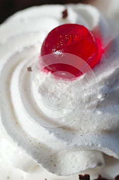 Whipped cream on the cake with a cocktail cherries close-up