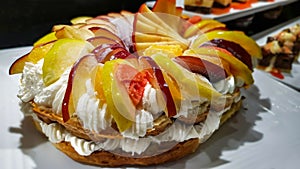 Whipped cream cake decorated with pear, apple and peach wedges