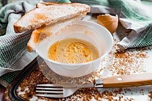 Whipped with a fork and mixed raw egg broken into a white bowl with yolk and protein, next to the shell, fork and towel