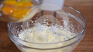 Whipping cream with electric mixer. Add yolk while mixing cream in glass bowl. Home bakery.