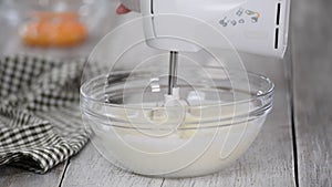 Whipping of cream in a glass bowl with mixer.