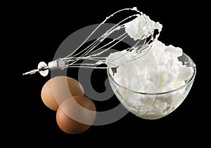 Whipping eggs with whisk and eggs isolated on black background
