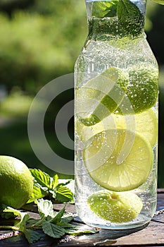 A whirl of mint and lime in a bottle with a homemade mojito cocktail on a summer day in the garden