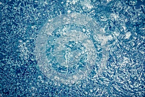 Whirling water background with bubbles and ripples in swimming pool in blue toned colors