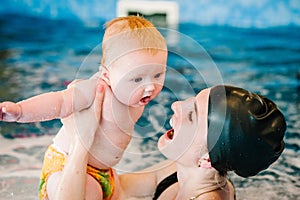 Whirlpool, jacuzzi. Diving baby in the paddling pool. Young mother, swimming instructor and happy little girl in pool. Learn