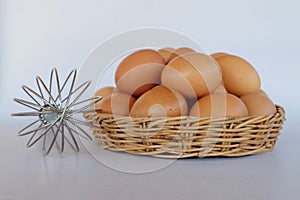 Whisk and eggs in rattan basket.