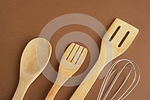 whisk and wooden spatula on brwn background copy space