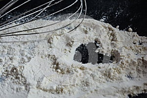 Whisker tapping on the flour poured over a white surface