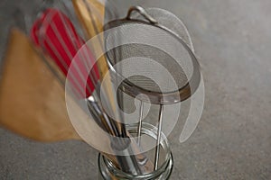 Whisker, wooden spoon, strainer and spatula on glass jar