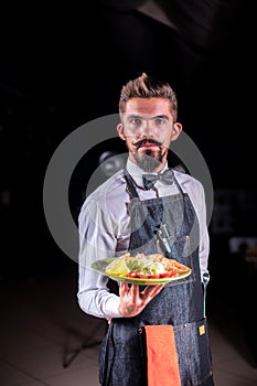 Whiskered flunkey helpfully serves cooked dish at a festive event. photo