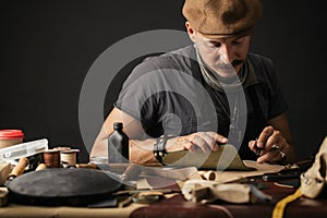 Whiskered shoemaker with making measurments in patterns at table in workshop