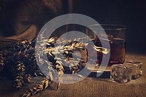 Whiskey on background with wheat straws toning photo