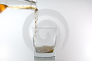 Whiskey being poured into a glass against white background