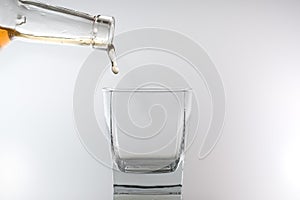 Whiskey being poured into a glass against white background
