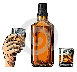 Whiskey bottle and hand holding glass.