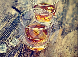 Whiskey bourbon with ice on wooden texture background.