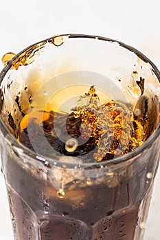 whiskey cocktail with cola and ice in a transparent glass with splashes
