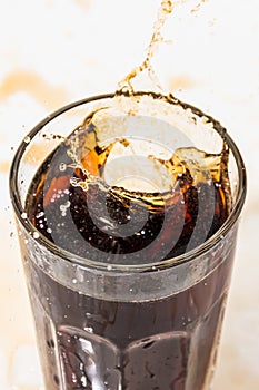 whiskey cocktail with cola and ice in a transparent glass with splashes