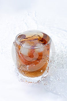 whiskey cocktail with cola and ice in a transparent glass with splashes