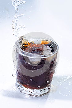 whiskey cocktail with cola and ice in a transparent glass with splashes