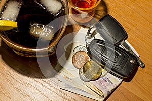 Whiskey, cocktail, money and car keys at the bar