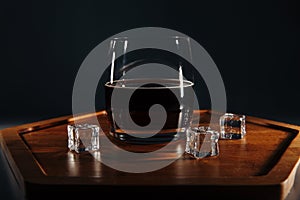Whiskey with coke and ice on a wooden tray