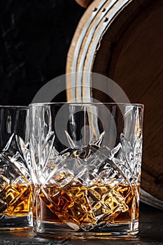 Whiskey in a glass with a barrel. Bourbon whisky and a cask on a dark background photo