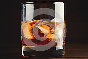 Whiskey in glass with cubes of ice on dark background close up