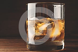 Whiskey in glass with cubes of ice on dark background close up