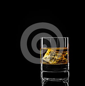 Whiskey glass with golden alcohol and ice cube