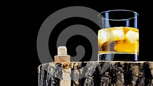 Whiskey in a glass with ice on a black background. Scotch whiskey on wooden