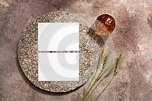 Whiskey glass with ice, blank white business card mockup with elements of granite and ears of wheat. Male background. Alcohol