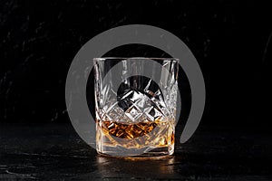 Whiskey in a glass with ice. Bourbon whisky on rocks on a black slate background photo