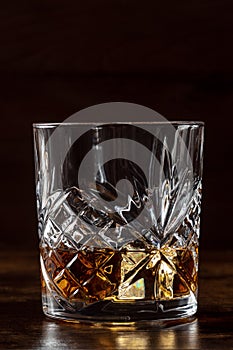 Whiskey in a glass with ice. Bourbon whisky on rocks on a dark background photo