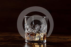Whiskey in a glass with ice. Bourbon whisky on rocks on a dark background photo