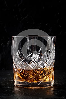 Whiskey in a glass with ice. Bourbon whisky on rocks on a dark stone background photo
