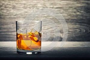 Whiskey glass and ice on wooden background