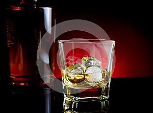 Whiskey glass near bottle on light tint red disco