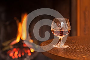 Whiskey in glass on table by open fire