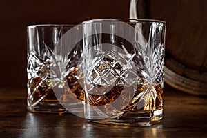 Whiskey in glasses with a barrel. Bourbon whisky and a cask on a dark background