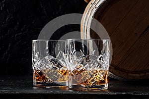 Whiskey in glasses with a barrel. Bourbon whisky and a cask on a dark background photo