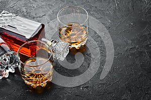 Whiskey in glasses on black stone table.