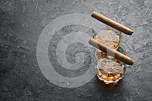 Whiskey in glasses and Cuban cigars on a black stone table. Top view.