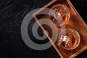 Whiskey in glasses with ice. Bourbon whisky on rocks on a black slate background photo