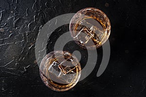 Whiskey in glasses with ice. Bourbon whisky on rocks on a black stone background photo
