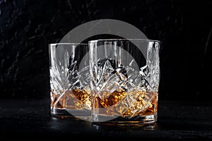 Whiskey in glasses with ice. Bourbon whisky on rocks on a dark background photo