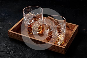 Whiskey in glasses with ice. Bourbon whisky on rocks on a dark background photo
